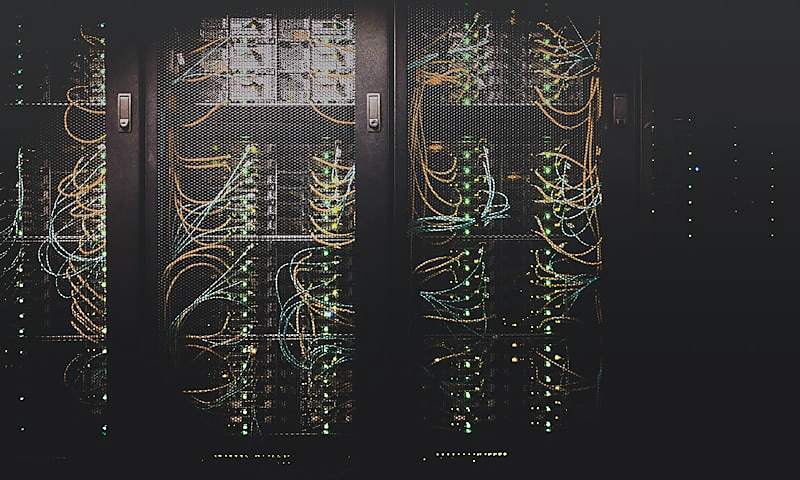 IT technician working at a server rack and patch panel, representing network design and management.