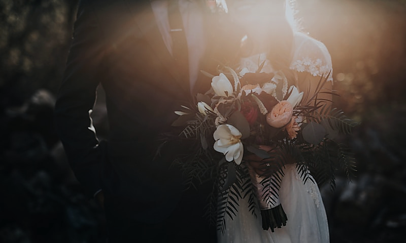 Wedding couple sharing a quiet moment while a film crew captures the scene, representing wedding videography.
